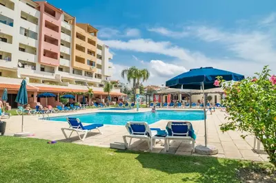 a pool at a resort with chairs and an umbrella at BelaVista Tenis SweetHouse in Albufeira
