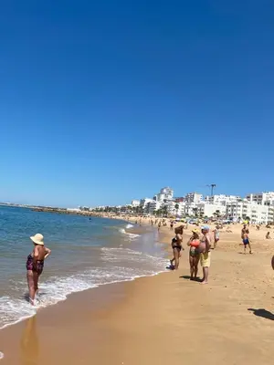 a group of people walking on the beach at Beachfront flat with pool in Quarteira