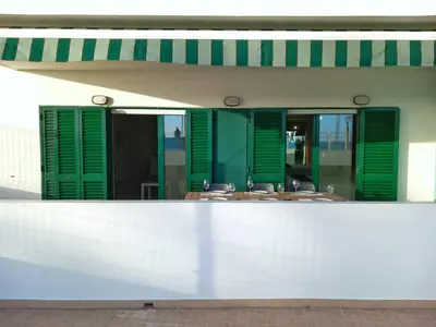 a restaurant with green shuttered windows and tables at Beachfront flat with pool in Quarteira