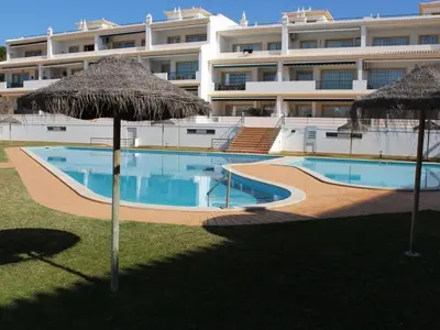 a large building with a swimming pool and two umbrellas at Beach&Golf Vilamoura Apartment in Vilamoura