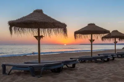 a group of beach chairs with umbrellas on the beach at Beach&Golf Vilamoura Apartment in Vilamoura