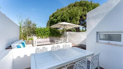 a patio with a table and chairs and an umbrella at Relaxing Beach House in Alfamar by LovelyStay in Albufeira