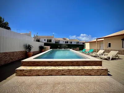 a swimming pool with stairs and chairs next to a house at Albufeira Summer Villa 2 with Pool by Homing in Albufeira