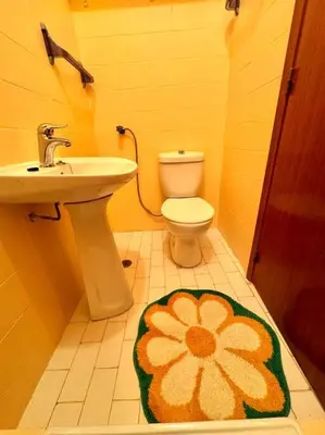 a bathroom with a sink and a toilet with a flower rug at Apartamento Faro - T3 in Faro