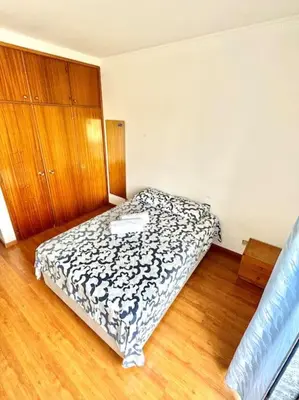 a bed in a room with a wooden floor at Apartamento Faro - T3 in Faro