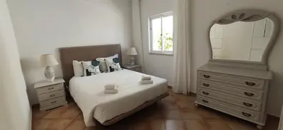 a bedroom with a bed with a mirror and a dresser at Casa Golfinho, Albufeira in Albufeira
