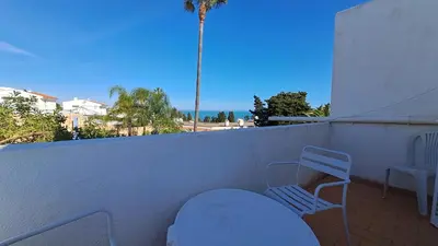 a balcony with a chair and a table and a palm tree at Albufeira Seaview 4 Beach HOUSE in Albufeira
