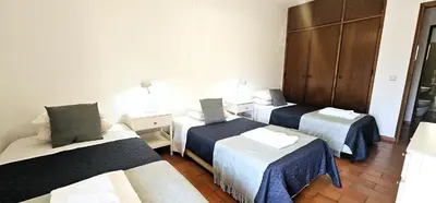 a hotel room with three beds in a room at Beach House Vidinha in Albufeira
