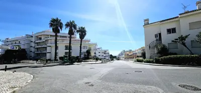 an empty street with palm trees and buildings at Beach House Vidinha in Albufeira