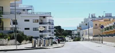 a city street with cars parked next to tall buildings at Beach House Vidinha in Albufeira