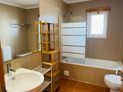 a bathroom with a sink and a tub and a toilet at Vila Nalia in Albufeira