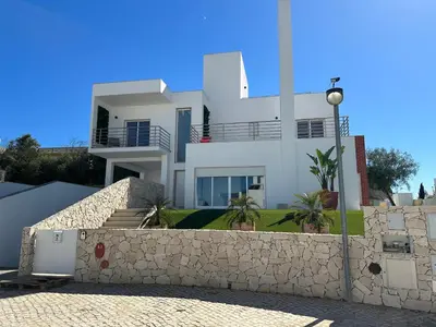a large white house with a stone wall at Vila Nalia in Albufeira