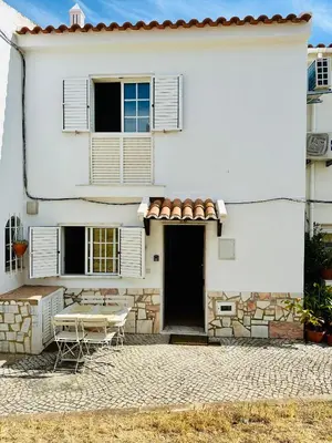 a white house with a table and chairs in front of it at Casa Esperança in Albufeira