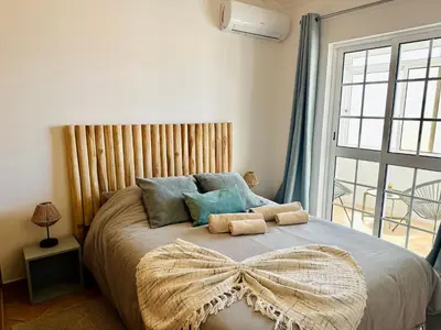 a bedroom with a large bed with a large window at Casa Esperança in Albufeira