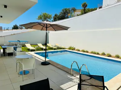 a swimming pool with an umbrella and tables and chairs at Vila Elvia in Albufeira