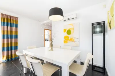 a white dining room with a white table and chairs at Villas Novochoro - Small Garden by DreamvillasAlbufeira in Albufeira