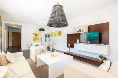 a living room with white furniture and a flat screen tv at Villas Novochoro - Small Garden by DreamvillasAlbufeira in Albufeira