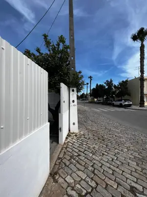a fence on the side of a street with a pole at O Limoeiro - 154949/AL in Faro