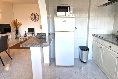 a kitchen with a white refrigerator and a table at Casa Kari in Albufeira