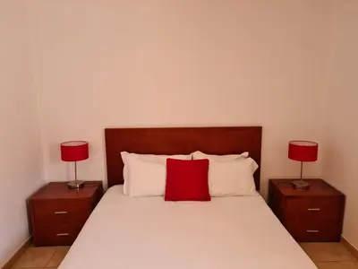 a bedroom with a bed with two red lamps at APARTAMENTOS CABRITA in Olhos de Água