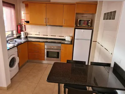 a kitchen with wooden cabinets and a white refrigerator at APARTAMENTOS CABRITA in Olhos de Água