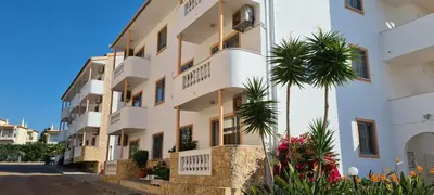 a building with a palm tree in front of it at APARTAMENTOS CABRITA in Olhos de Água