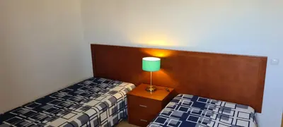 a bedroom with two beds and a lamp on a night stand at APARTAMENTOS CABRITA in Olhos de Água