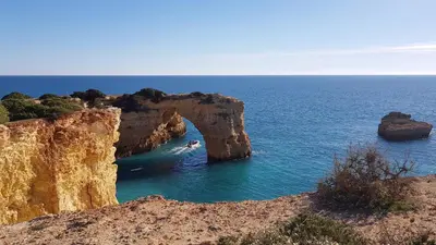 an arch in the ocean with a person in the water at Casa Catarina in Albufeira
