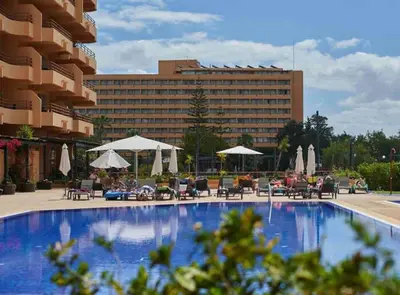 a hotel with a swimming pool with chairs and umbrellas at Estúdio Vista Mar em Vilamoura in Quarteira