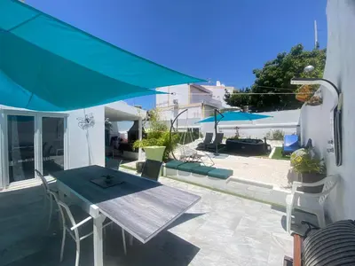a patio with a table and a blue umbrella at Casa eden garden in Albufeira