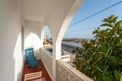 a balcony with a blue chair and a view of the ocean at Blife Faya private rooms in Faro
