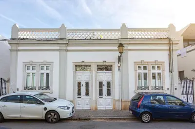 two cars parked in front of a white building at Blife Galya private rooms in Faro