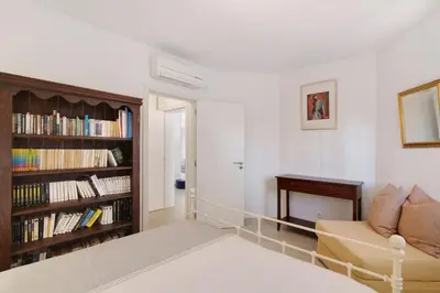 a living room with a couch and a book shelf with books at Townhouse Ramas in Vale do Lobo