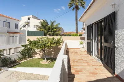 a white house with black doors and a courtyard at Vila Branca - V3 by HD PROPERTIES in Quarteira
