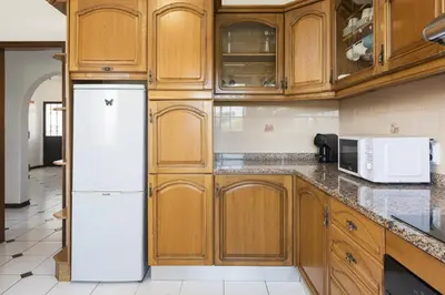 a kitchen with wooden cabinets and a white refrigerator at Vila Branca - V3 by HD PROPERTIES in Quarteira