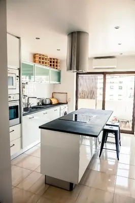 a kitchen with white cabinets and a table in it at Casa Gulbenkian - Modern apartment by HD in Faro