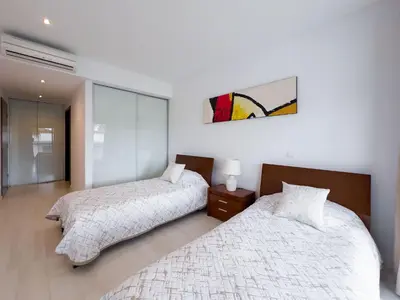 a bedroom with two beds and a painting on the wall at Стильный апартамент Т2 Quarteira in Quarteira