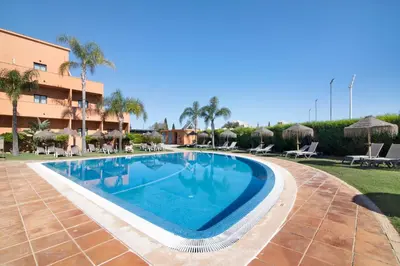 a swimming pool at a resort with palm trees at Casa Sol in Quarteira