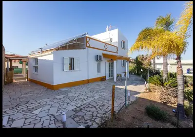 a white house with a palm tree in front of it at Blife Moustachya private rooms in Faro