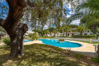 a swimming pool in a park with a tree at Albufeira Balaia Golf Vilage 5 With Pool by Homing in Albufeira