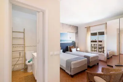a hotel room with two beds and a bathroom at Apartamento Sunny in Quarteira