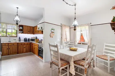 a kitchen with wooden cabinets and a table with chairs at Sunshine House in Faro