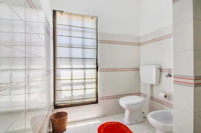 a white bedroom with a bed with two hats on it at Sunshine House in Faro