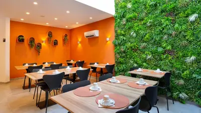 a restaurant with tables and chairs and a green wall at Faro Heart Suites in Faro
