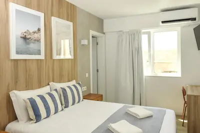 a bedroom with a white bed with blue and white pillows at Faro Heart Suites in Faro