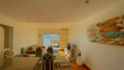 a living room with a table and a painting on the wall at Penthouse Triplex Marina T2 by HsR Vilamarina in Quarteira