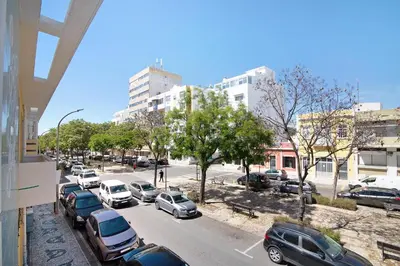 a city street with cars parked in a parking lot at Skipper House in Loulé