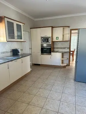 an empty kitchen with white cabinets and a refrigerator at Benvindo Villa by Umbral in Albufeira