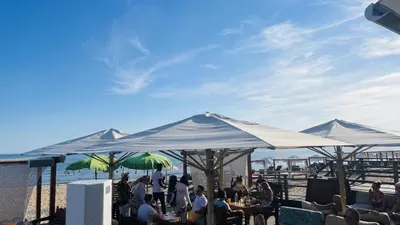 a group of people sitting at tables under umbrellas at Lotus by Check-in Portugal in Quarteira