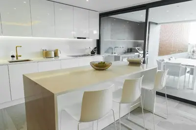 a kitchen with white cabinets and a counter with white chairs at Buganvilia - Luxury villa - private pool by HD in Vale Formoso